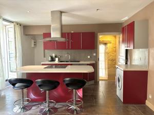 a kitchen with red cabinets and black bar stools at Appartement duplex in Lectoure