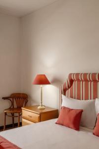 a bedroom with a bed with a lamp and a chair at Sunset Bay São Martinho do Porto in São Martinho do Porto