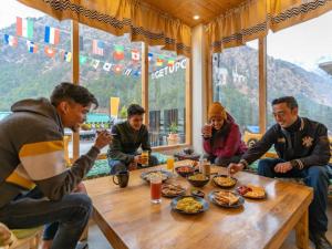 a group of people sitting around a table eating food at The Hosteller Kasol, Parvati Valley in Kasol