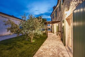 a walkway between two buildings with a tree at Villa Katja near Pula with whirlpool only 3 km from the beach in Krnica +48 photos
