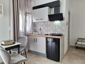 a kitchen with white cabinets and a sink and a table at Vithos in Agnontas
