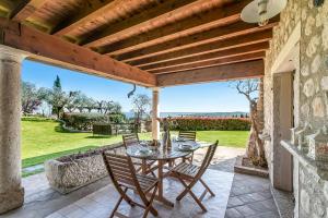 a patio with a table and chairs under a wooden ceiling at Agriturismo Cascina Crocelle - Lake View and Heated Pool in Padenghe sul Garda