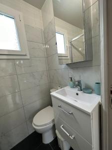a white bathroom with a toilet and a sink at Cozy, bright apartment - Disney - private parking in Rosny-sous-Bois