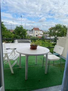 a white table and chairs on a balcony with a view at Cozy, bright apartment - Disney - private parking in Rosny-sous-Bois