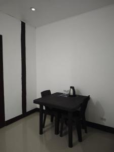 a black table and chair in a room with a white wall at Hola El Nido in El Nido +4 photos