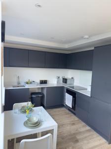 a kitchen with blue cabinets and a white table at Modern and Stunning 1 Bed near Old Trafford and City Centre in Manchester +10 photos