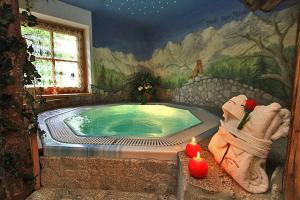 un cuarto de baño con jacuzzi y una pintura en Hotel Garni San Nicolò, en Pozza di Fassa
