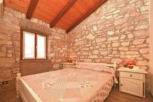 a bedroom with a bed in a stone wall at Apartmani Petar Stojnić in Vabriga