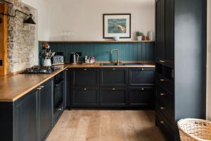 a kitchen with black cabinets and a sink at Sweet Pea Cottage in Tideswell