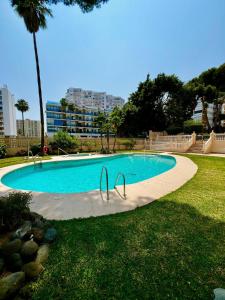 a swimming pool with two metal tracers in the grass at 2 Bedroom Apartment in Puerto Marina in Benalmadena Costa