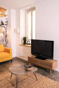 a living room with a flat screen tv on a table at Au Coeur du marché - Hyper centre Dijon - Terrasse in Dijon