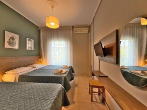 a hotel room with two beds and a mirror at Hotel Thermaikos in Korinos