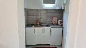 Una pequeña cocina con gabinetes blancos y un fregadero. en Studio apartment Sara, en Mostar