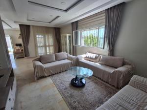 a living room with two couches and a glass table at Villa lucky in Hammamet