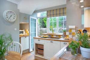 a kitchen with a clock on the wall at Dairy Cottage in Seaton