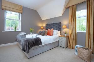 a bedroom with a large bed and two windows at Dairy Cottage in Seaton