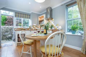 a kitchen with a table and chairs and windows at Dairy Cottage in Seaton