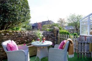 a patio with a table and two chairs with pink pillows at Dairy Cottage in Seaton +15 photos