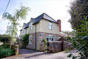 an old stone house with a fence in front of it at Dairy Cottage in Seaton