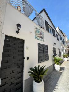 una casa blanca con una puerta negra y plantas en Le Tre Perle Ischia, en Isquia