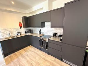 une cuisine avec des armoires noires et un plancher en bois dans l'établissement Luxury 1 bed - 6 Queen Street Abingdon - Centrally located parking subject to availability, à Abingdon