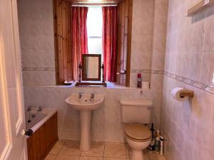 a bathroom with a sink and a toilet and a window at Laundry Cottage in Lanark +13 photos