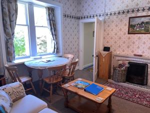 un salon avec une table et une cheminée dans l'établissement Laundry Cottage, à Lanark