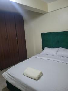 a bedroom with a white bed and wooden cabinets at Baylynn Homes in Homa Bay