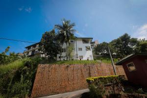 a white house with a palm tree behind a retaining wall at Shalom Residence Kandy in Kandy