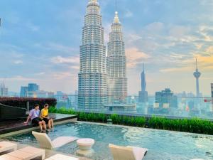 two people sitting on a rooftop with the petronas towers at STAR KLCC By Comfort Hospitality in Kuala Lumpur