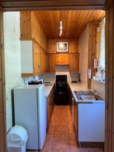 une cuisine avec des armoires en bois et un réfrigérateur blanc dans l'établissement Laundry Cottage, à Lanark