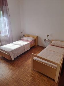 a room with three beds and a wooden floor at Casa Fontana Rossa 2 in Arizzano