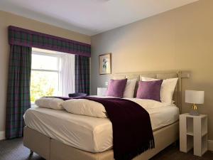 a bedroom with a large bed with purple pillows at Kilfinan Hotel in Kilfinan