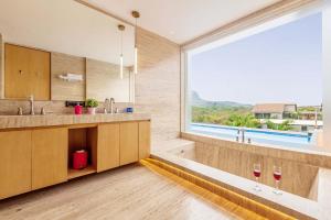 ロナバラにあるStayVista's Villa 107 at Canary Farms - Pure Veg with Huge Lawn, Pool and Home Theatreの2つのワイングラスと大きな窓のあるバスルーム