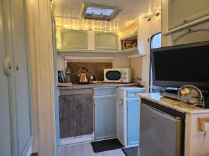 Una cocina de RV con gabinetes azules y un televisor. en Cosy Caravan Walkers Ramblers Fishermen Cyclists, en Abermule 20 fotos más