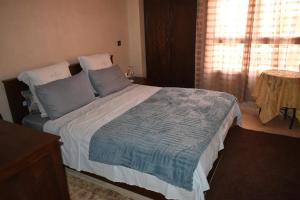 a bedroom with a bed with blue pillows and a window at Marrakech Sakan Annakhil im6 n31 in Marrakesh