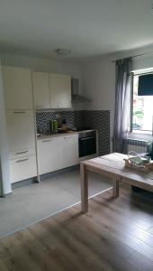 a kitchen with white cabinets and a wooden table at Apartment Aleksandar in Mošćenička Draga