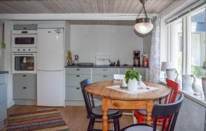 锡姆里斯港2 Bedroom Lovely Home In Simrishamn的厨房配有木桌、椅子和冰箱