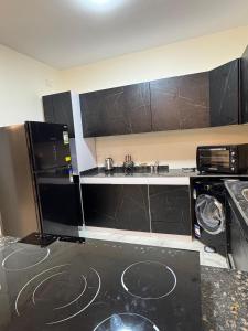 a kitchen with black cabinets and a black refrigerator at قصر الأحلام فيلا أول سكن بمسبح خاص ومساحة 2000 متر in El Alamein +18 photos