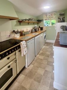a kitchen with white appliances and a tile floor at Locks Lane Cottage in Geldeston