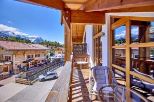 a balcony with a table and chairs and a view of a city at Mountain Safari Garmisch - Spacious, scenic and steps from adventure in Garmisch-Partenkirchen