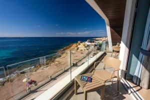a balcony with a view of the ocean and a beach at Bugibba - Central Luxury Seafront, only for family in St. Paul's Bay