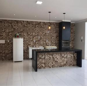 a kitchen with a stone wall and a refrigerator at RR Deck Betolandia in Juazeiro do Norte