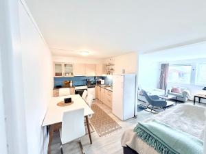 a kitchen and living room with a table and a refrigerator at Cozy apartment close to nature in Tromsø