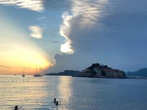 a group of people swimming in the water at sunset at Apartments Lungo Mare in Sveti Stefan