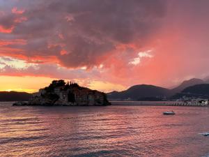 a house on an island in the water at sunset at Apartments Lungo Mare in Sveti Stefan