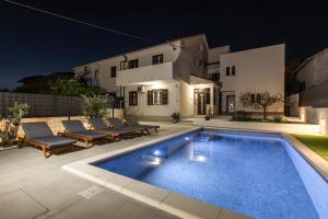 a swimming pool in front of a house at night at Poolhouse Domus in Solin