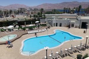 una gran piscina en un complejo con mesas y sillas en Amram Sea Side Eilat Luxury, en Eilat