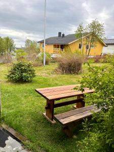 a wooden picnic table in a yard with a yellow house at Cozy apartment close to nature in Tromsø