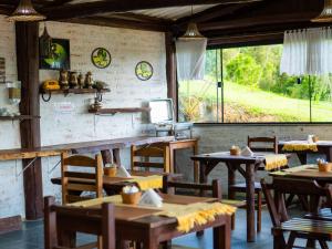 un ristorante con tavoli e sedie in legno e finestre di Pousada Natureza da Terra a Monte Verde